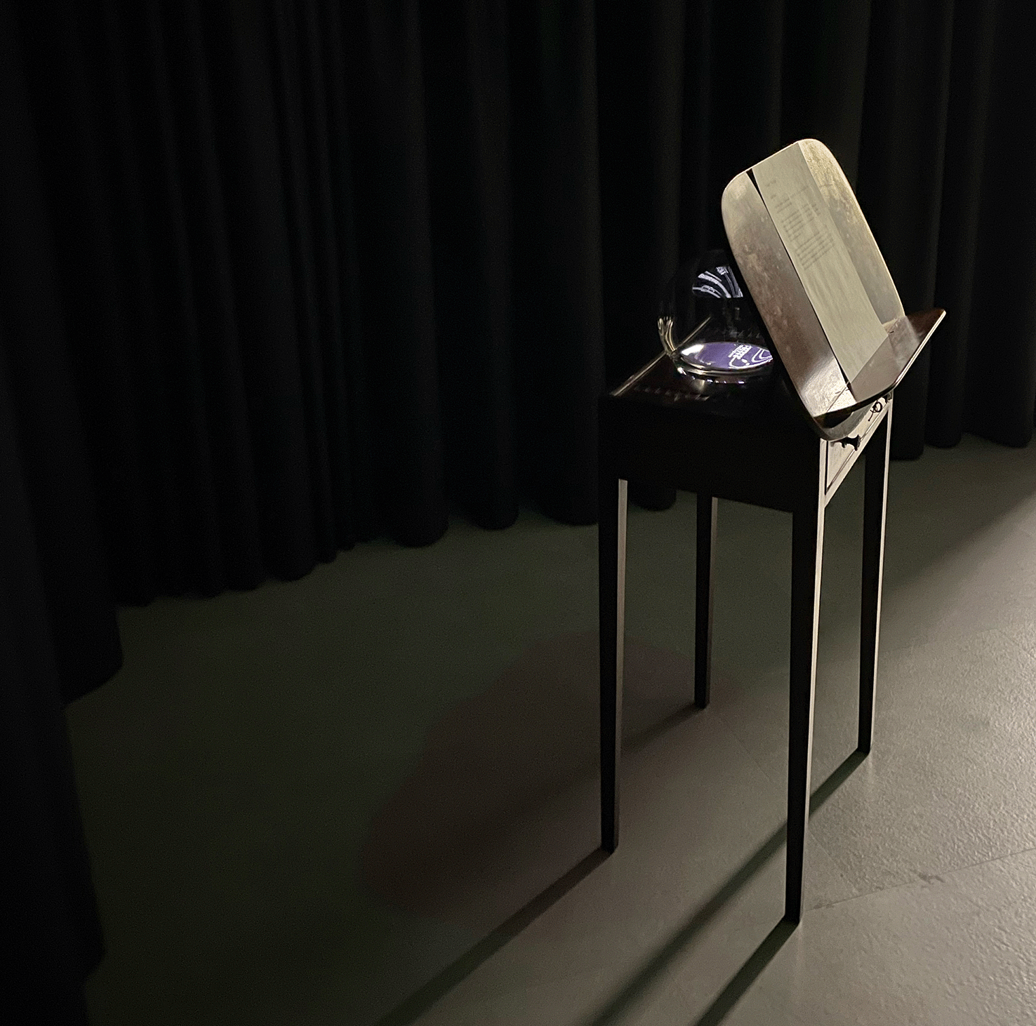 Visions | Vestiges (2023). The notational sculp- ture was assembled from a Victorian-Era music stand, a handblown glass sphere, water, and an iPad displaying animated notation generated in the Decibel ScorePlayer.